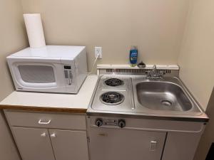 a small kitchen with a sink and a microwave at The King's Motel in Sundre +17 photos