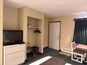 a room with a flat screen tv sitting on a dresser at The King's Motel in Sundre