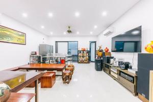 a large kitchen with white walls and wooden tables at KEY'N'S HOUSE FLC Sầm Sơn in Sầm Sơn