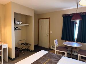 a room with a bed and a table and chairs at The King's Motel in Sundre