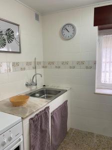 a kitchen with a sink and a clock on the wall at Las Tres Luces Casa 1 in Llanes +15 photos