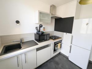 a white kitchen with a sink and a microwave at Le St Mens in Gap +15 photos