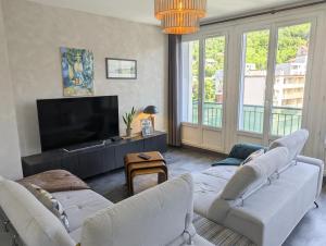 a living room with two white couches and a flat screen tv at Le St Mens in Gap