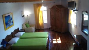 a living room with a green bed and a television at Mykonos Rooms in Agios Stefanos