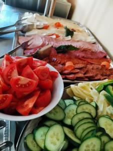 a tray of food with tomatoes and cucumbers and meat at Nautica Stúdió by HelloBalatonlelle in Balatonlelle