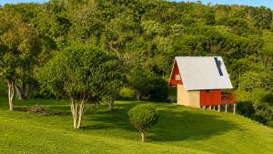 a red and white barn on a hill with trees at Chalés Recanto da Serra in Bocaina do Sul