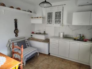 a kitchen with white cabinets and a sink and a table at Trikeri pleasant stay in Ayía Kiriakí