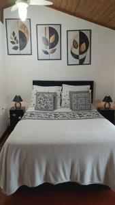 a bedroom with a white bed with pictures on the wall at Chalé Aconchego da Lapinha Vista para Montanhas Piscina e Natureza in Santana do Riacho