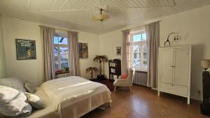 a bedroom with a bed and a chair and windows at Helle Ferienwohnung - Südeifel bei Neuerburg in Ammeldingen