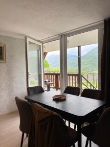 a dining room table with chairs and a large window at Racha Hills in Ambrolauri