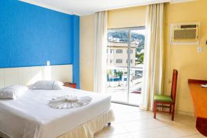 a bedroom with a bed with a blue wall and a window at Acrópolis Marina Hotel in Angra dos Reis