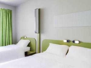 a bedroom with two white beds and a green curtain at Ibis Budget Braga Centro in Braga +42 photos