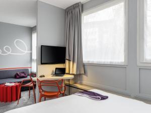 a hotel room with a desk with a laptop and a window at ibis Styles Paris Velizy in Vélizy-Villacoublay