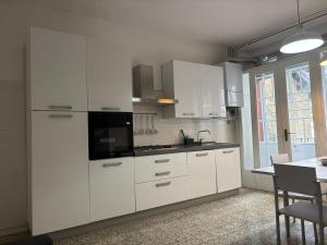 a white kitchen with white cabinets and a table at Casa Limmy in Intra