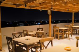 a row of tables and chairs on a rooftop patio at night at Farida Palace Hotel in Al Aqālitah