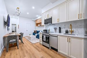 a kitchen and living room with white cabinets and a table at Casa Hotels Gerrard Newly Built Suite Steps to Transit in Toronto