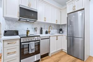a kitchen with white cabinets and a stainless steel refrigerator at Casa Hotels Gerrard Newly Built Suite Steps to Transit in Toronto