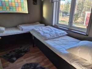 two beds in a room with two windows at Åker Lilläng Solviken in Skillingaryd
