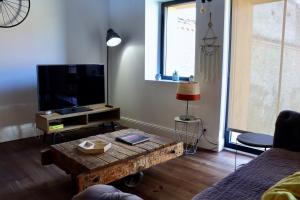 a living room with a coffee table and a flat screen tv at La Maison d'Augustin in Mont-de-Marsan