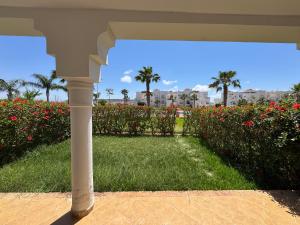 a white porch with a field of grass and flowers at Saidia Marina in Saïdia