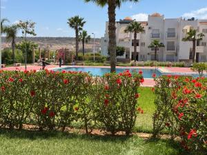a garden with red flowers in front of a swimming pool at Saidia Marina in Saïdia