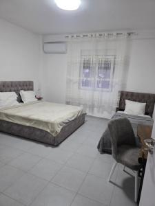 a white room with two beds and a chair at Casa Del Sol Pogradec in Pogradec