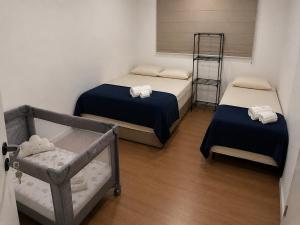 a bedroom with two beds and a baby crib at 7 min de Cabo Frio AP LISBOA in São Pedro da Aldeia +52 photos