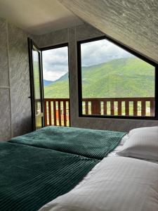 a bedroom with a bed and two windows with a view at Racha Hills in Ambrolauri