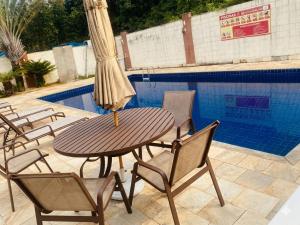 a table with chairs and a umbrella next to a pool at Acalmaria Residence in Macaé