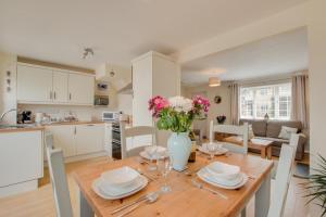a kitchen and dining room with a wooden table with flowers at 2 Bed in Instow oc-stones in Instow
