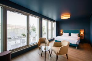 a hotel room with a bed and chairs and windows at Hôtel de la Cité in Nantes +53 photos