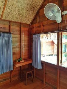 a room with wooden walls and a window with a fan at Lipe Beach Resort in Ko Lipe