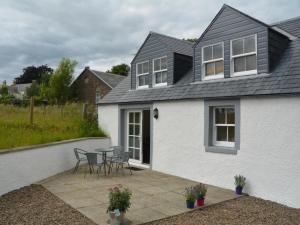 a white house with a patio with chairs and a table at 1 Bed in Kelso oc-52538 in Morebattle +5 photos