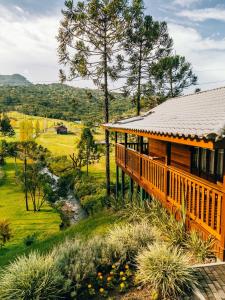 a wooden house with a deck and a river at Rancho Canto da Lua in Urubici