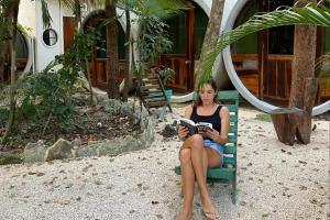 a woman sitting in a chair reading a book at Hostal Mulut Tulum in Tulum
