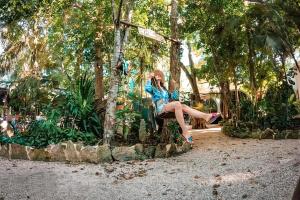 a woman sitting on a bench talking on a cell phone at Hostal Mulut Tulum in Tulum