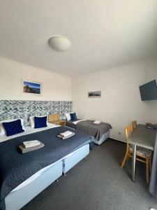 a room with two beds and a table and a desk at Pension Kiwi in Mikulov