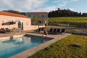 a woman sitting in a swimming pool next to a vineyard at Canhoto Douro in Marco de Canaveses