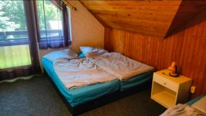 a bed in a room with a wooden wall at CHALET Dom z basenem in Lutol Mokry +16 photos