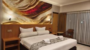 a bedroom with a bed with a painting on the wall at Votel Manyar Resort Banyuwangi in Ketapang +34 photos