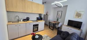 a kitchen with white cabinets and a living room at Odpocznij w Centrum in Wałbrzych