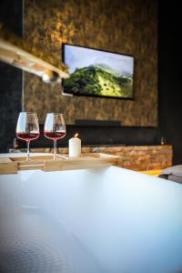 two glasses of wine sitting on a table with a television at Ascent Lodge -Jacuzzi si Panoramic View in Petreasa