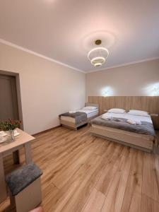 two beds in a large room with wooden floors at Alcha Hotel Karakol in Karakol