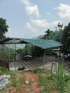 a pavilion with a green roof in a field at Grand Munnar Rooms in Munnar +24 photos