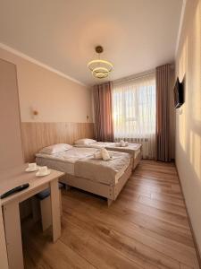 a bedroom with two beds and a desk and a window at Alcha Hotel Karakol in Karakol