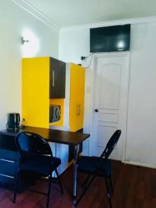 a kitchen with a table and two chairs and yellow cabinets at Alojamiento Cabañas in Pucón
