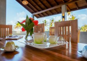 a wooden table with two tea cups and a vase with flowers at Cavendish Polhena in Matara