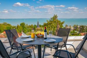 a table with a bottle of wine and glasses on a balcony at Apartman 360 in Balatonalmádi +58 photos