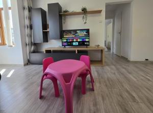 a pink stool in a room with a table and a tv at Konstanzer Podu Ros 11 - Spacious Apt - Palas Mall - AC in Iaşi