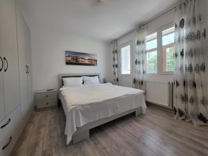a white bedroom with a bed and a window at Konstanzer Podu Ros 11 - Spacious Apt - Palas Mall - AC in Iaşi